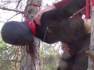 Atado hasta a un árbol al aire libre en seductor clothes&comma; vistiendo pantis y alto tobillo botas heels&comma; duro joder